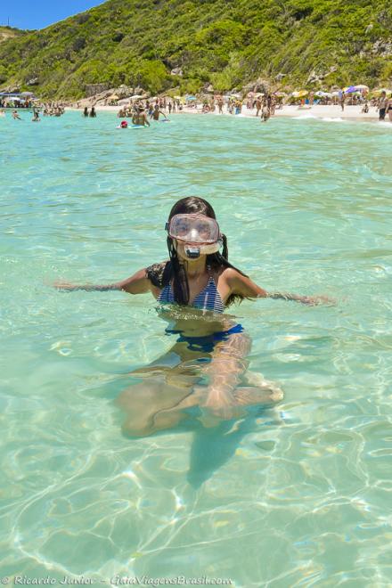 Imagem de uma menina nas águas transparentes da Praia do Pontal do Atalaia.